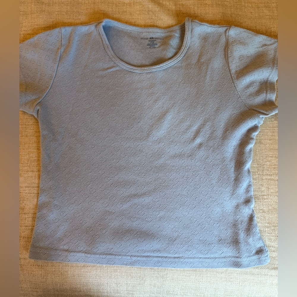 Brandy Melville Girls Light Blue Short Sleeve Top with Perforated Heart Pattern.